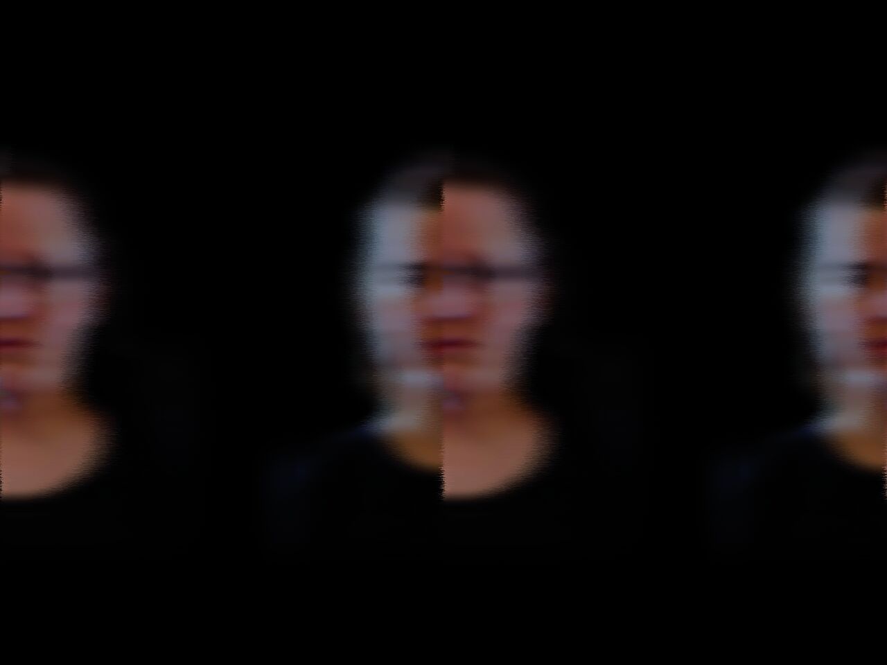 Ein Foto von drei Gesichtern, die verschwommen sind vor schwarzem Hintergrund.